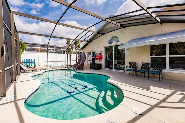 view of swimming pool featuring a fenced in pool, a lanai, a patio area, fence, and a water slide