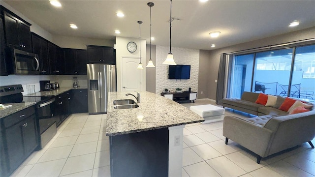 kitchen featuring decorative light fixtures, sink, stainless steel appliances, and a kitchen island with sink