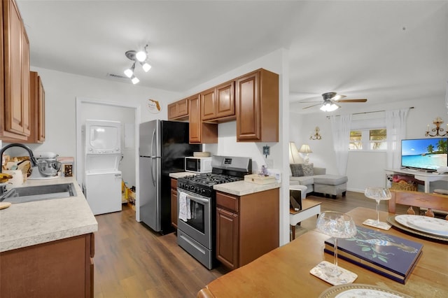 kitchen featuring ceiling fan, sink, dark wood-type flooring, stainless steel appliances, and stacked washer and clothes dryer