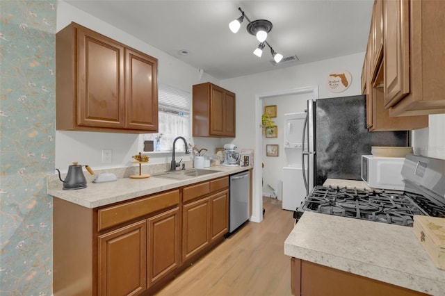 kitchen featuring dishwasher, range, light wood-type flooring, and sink