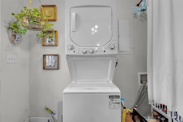 laundry area with stacked washer / drying machine and electric panel