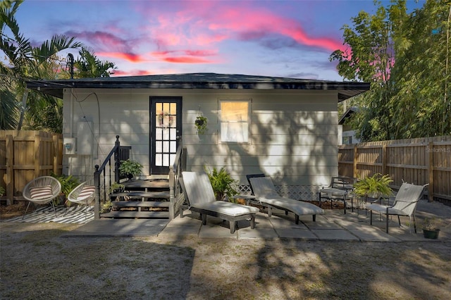 back house at dusk with a patio area