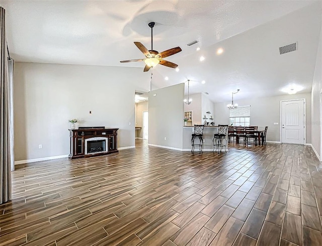 unfurnished living room with ceiling fan with notable chandelier, a textured ceiling, and high vaulted ceiling