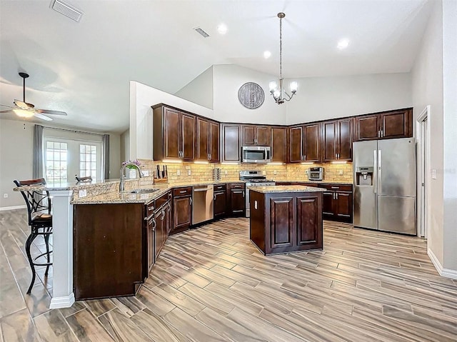 kitchen with sink, high vaulted ceiling, kitchen peninsula, pendant lighting, and appliances with stainless steel finishes