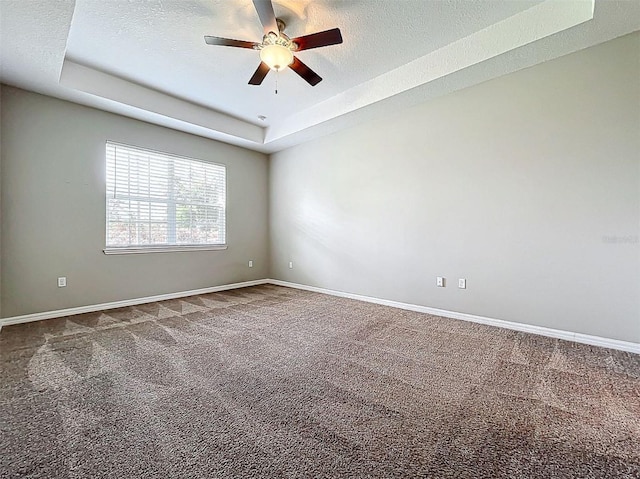 spare room featuring a textured ceiling, carpet floors, a tray ceiling, and ceiling fan