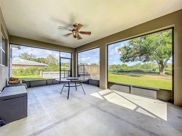 unfurnished sunroom featuring ceiling fan and a healthy amount of sunlight