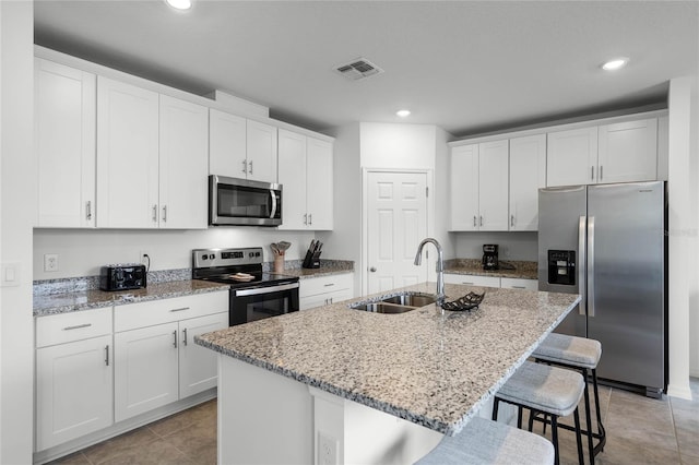 kitchen with appliances with stainless steel finishes, a center island with sink, white cabinetry, and sink