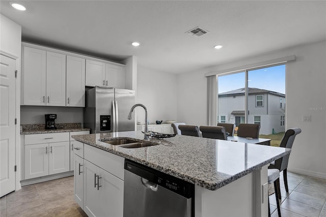 kitchen featuring sink, light stone counters, a kitchen island with sink, white cabinets, and appliances with stainless steel finishes