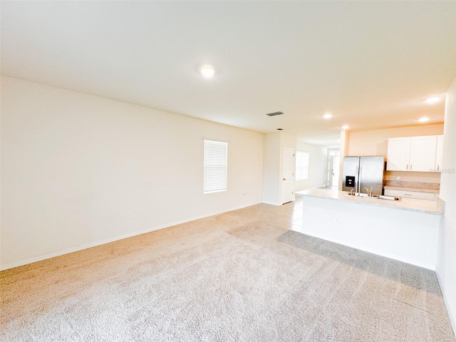 unfurnished living room with light carpet and sink