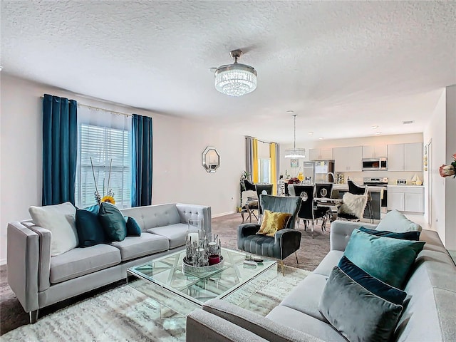 carpeted living room with a notable chandelier and a textured ceiling