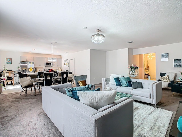 living room featuring a notable chandelier, a textured ceiling, and light carpet