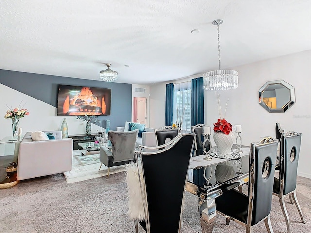 carpeted dining area with a notable chandelier and a textured ceiling