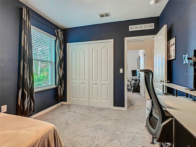 bedroom with a textured ceiling, carpet floors, and a closet