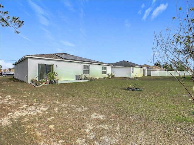 rear view of house featuring a yard and solar panels