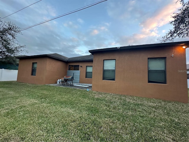 rear view of house with a lawn and a patio