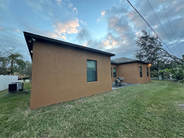 view of side of property with a yard, a patio, and cooling unit