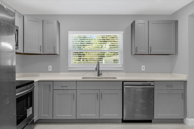 kitchen featuring gray cabinets, range, sink, and stainless steel refrigerator