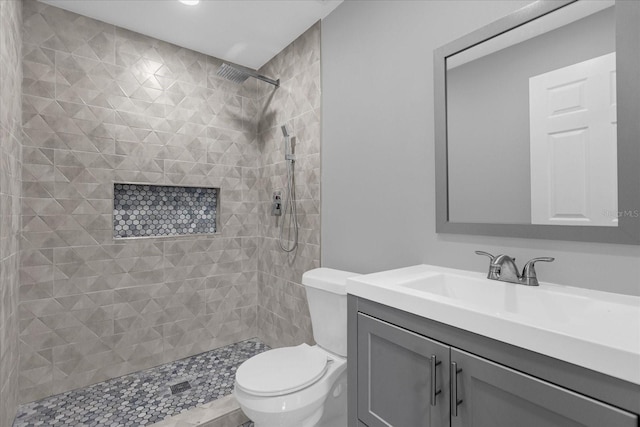 bathroom with tiled shower, vanity, and toilet