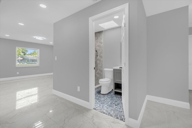 bathroom featuring a tile shower, vanity, and toilet