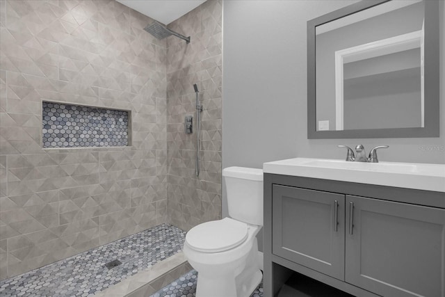 bathroom with vanity, toilet, and tiled shower