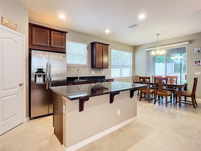 kitchen featuring stainless steel refrigerator with ice dispenser, sink, pendant lighting, an inviting chandelier, and a center island