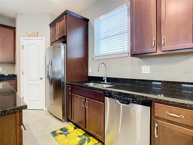 kitchen with dark stone countertops, sink, light tile patterned floors, and appliances with stainless steel finishes