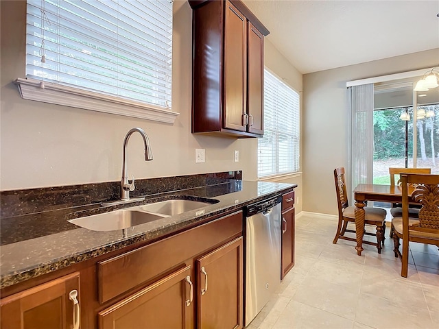 kitchen featuring dishwasher, light tile patterned flooring, dark stone counters, and sink