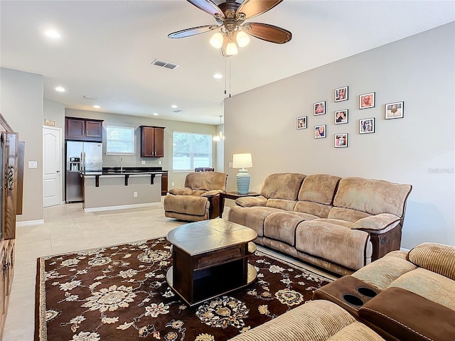 living room featuring light tile patterned floors, ceiling fan, and sink