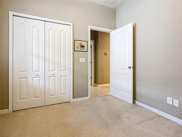 unfurnished bedroom with light carpet and a closet