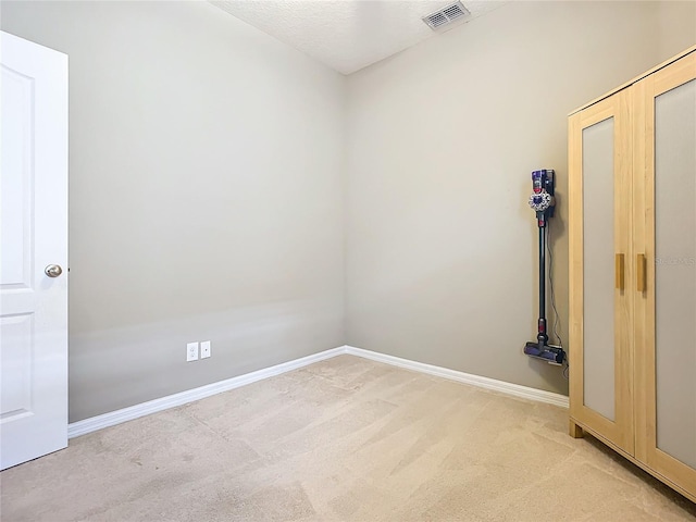 unfurnished room featuring light colored carpet and a textured ceiling