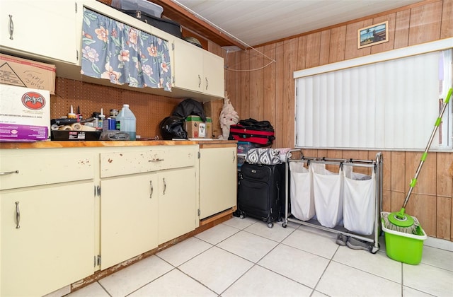 kitchen featuring light tile patterned floors and wood walls