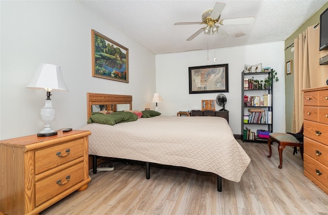 bedroom featuring ceiling fan, light wood-type flooring, and a textured ceiling