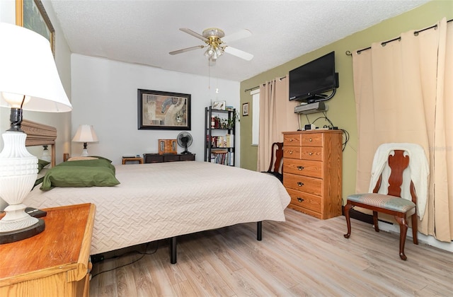 bedroom with ceiling fan, light hardwood / wood-style floors, and a textured ceiling