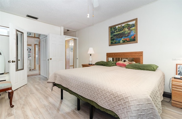 bedroom with ceiling fan, light hardwood / wood-style flooring, and a textured ceiling