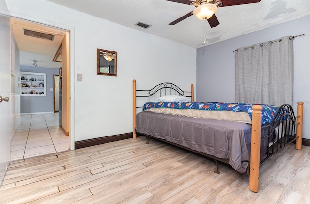 bedroom featuring a textured ceiling, light wood-type flooring, and ceiling fan