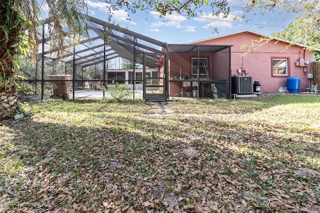 rear view of house with a lanai, central AC, and a lawn