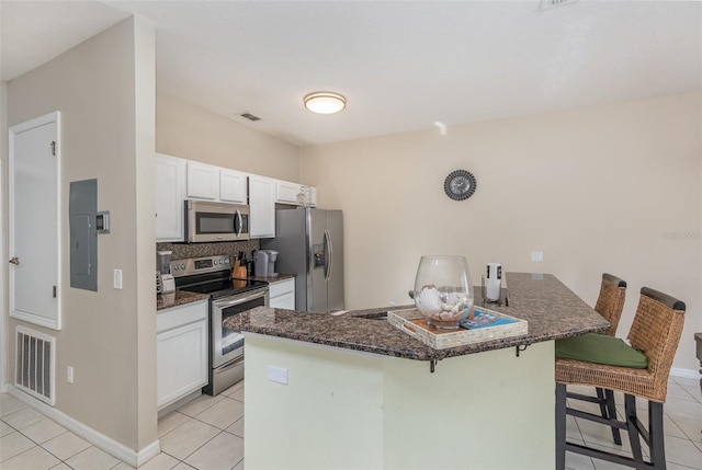 kitchen featuring light tile patterned flooring, a kitchen bar, white cabinetry, and appliances with stainless steel finishes