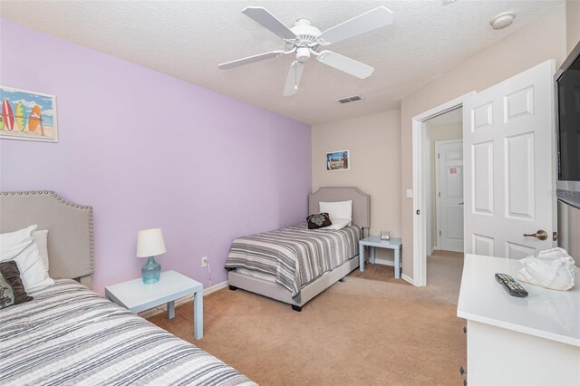 bedroom featuring ceiling fan, light colored carpet, and a textured ceiling