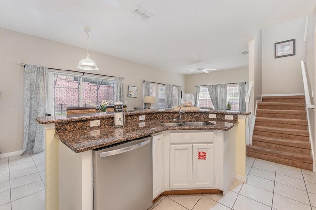 kitchen with stainless steel dishwasher, sink, pendant lighting, white cabinetry, and an island with sink