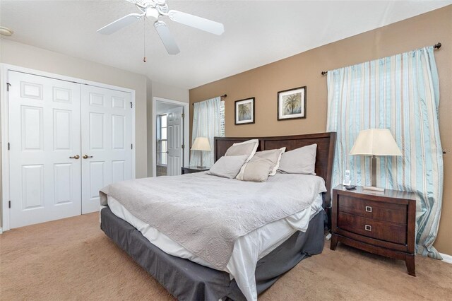 carpeted bedroom with ceiling fan and a closet