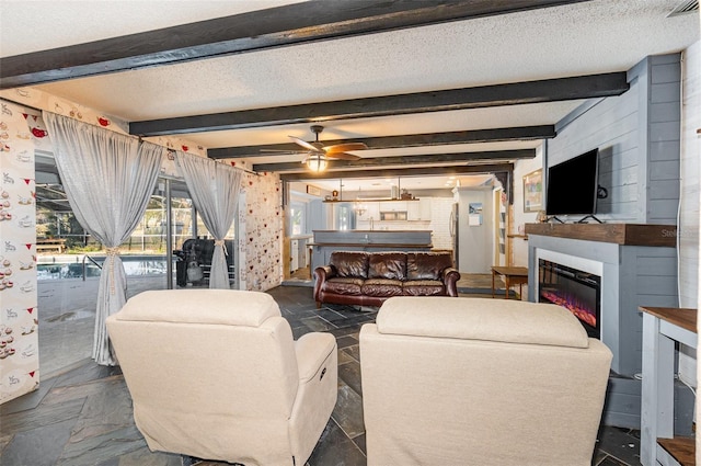 living room with beamed ceiling, a textured ceiling, and ceiling fan