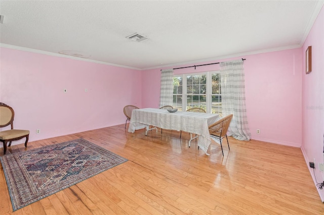 dining room featuring crown molding, a textured ceiling, and light hardwood / wood-style flooring