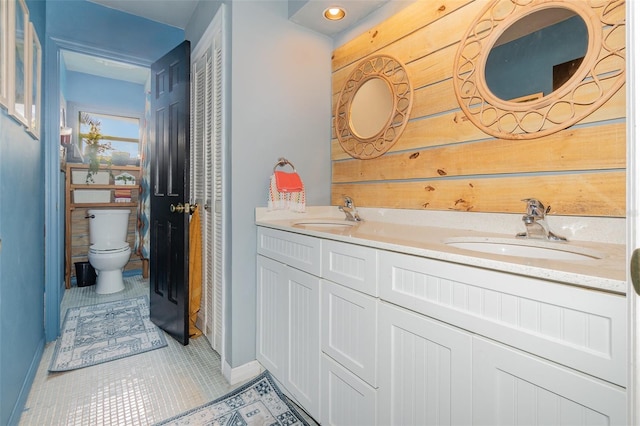 bathroom with vanity, tile patterned floors, wooden walls, and toilet