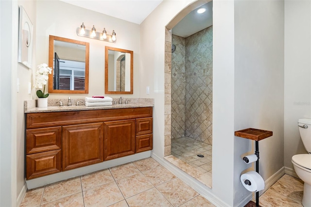 bathroom featuring vanity, tiled shower, tile patterned floors, and toilet