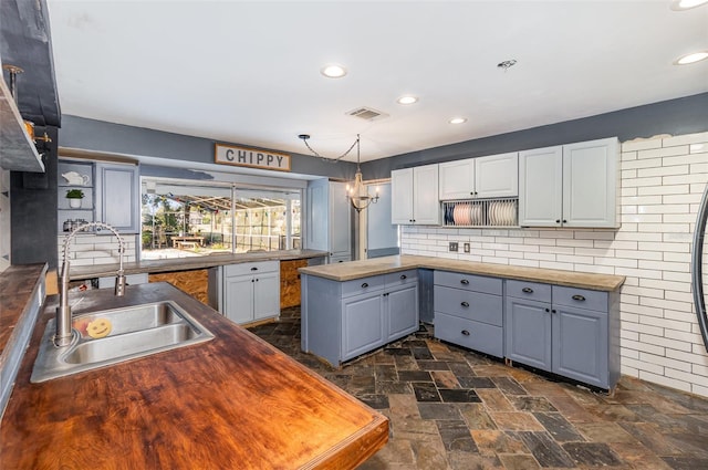 kitchen featuring gray cabinets, sink, white cabinets, decorative backsplash, and hanging light fixtures