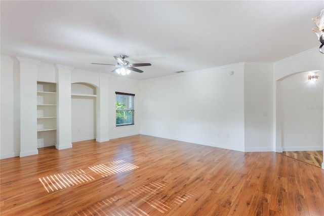 spare room with light wood-type flooring, built in features, ceiling fan, and ornamental molding