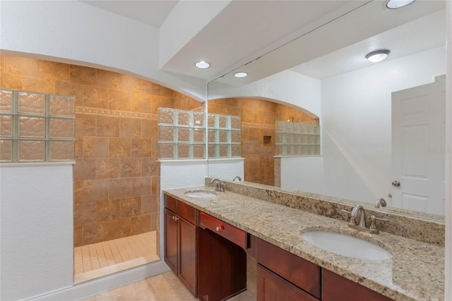 bathroom featuring tiled shower, vanity, and tile patterned flooring