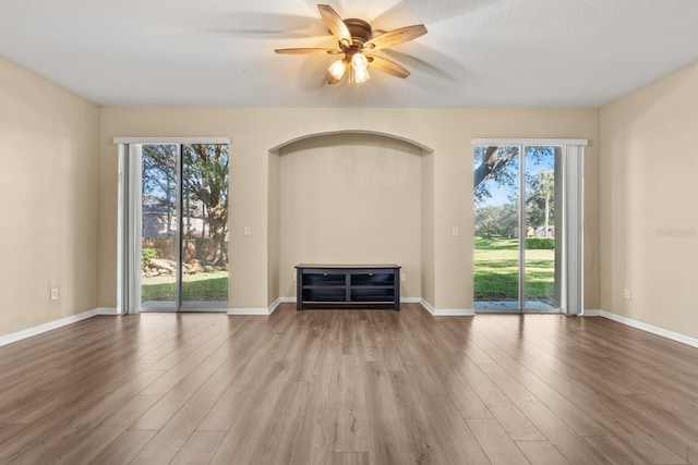 unfurnished living room featuring a wealth of natural light, ceiling fan, and hardwood / wood-style floors