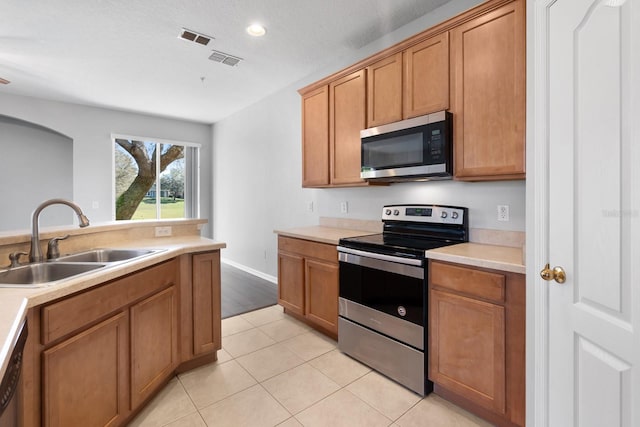 kitchen with a sink, stainless steel appliances, visible vents, and light countertops