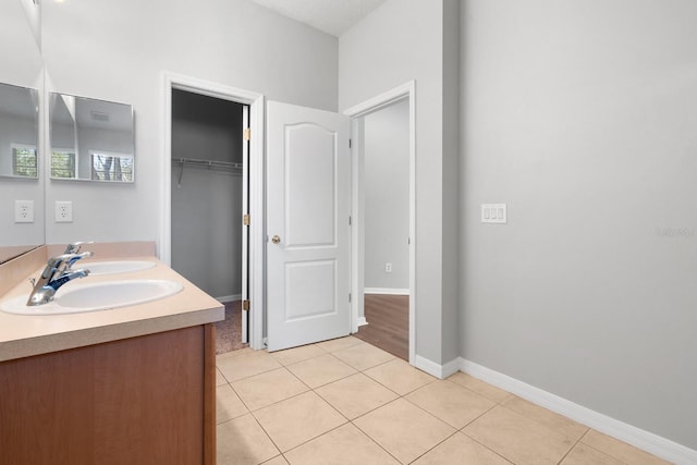 bathroom featuring a sink, baseboards, double vanity, and tile patterned floors